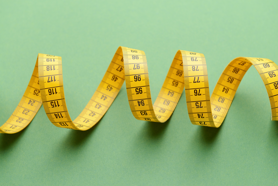 This image shows a winding measuring tape against a green background.