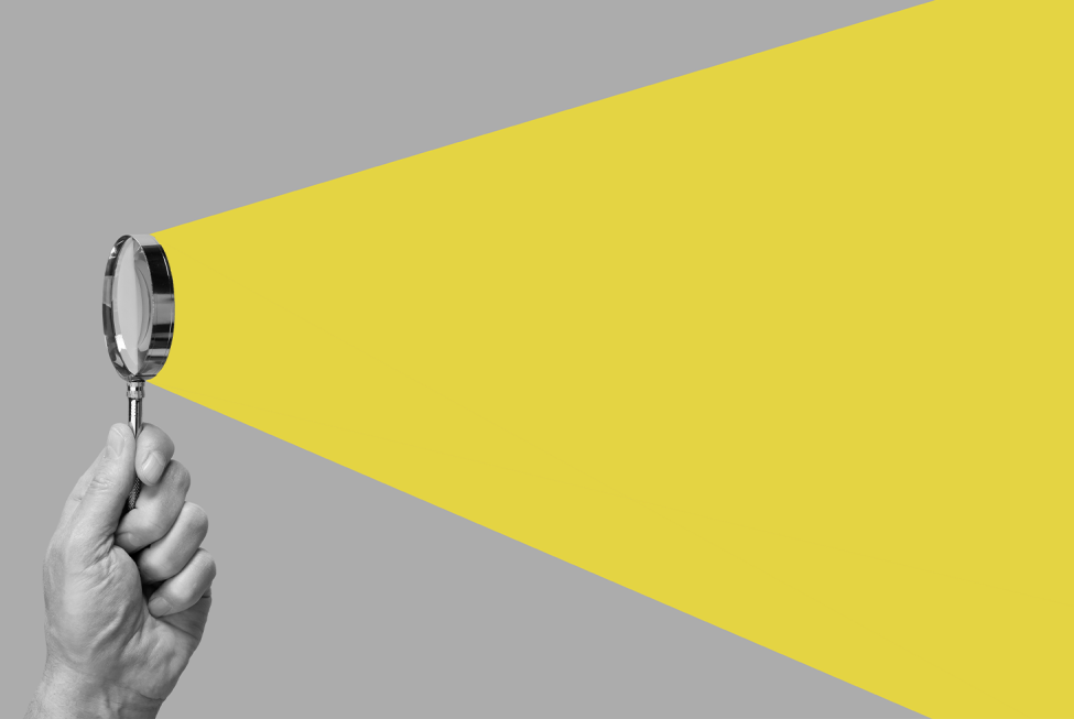 This image shows a hand holding a small magnifying glass from which emanates a yellow cone.